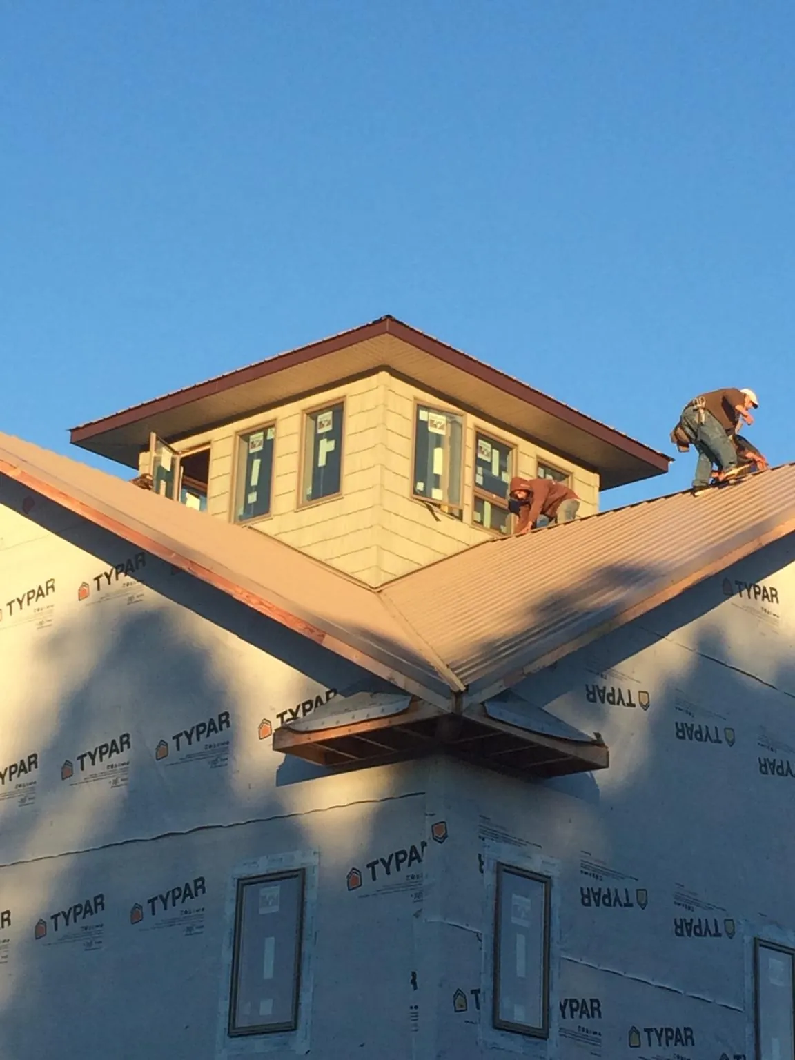 Roofers working around a rooftop cupola on a new metal roof at sunset — Roof Waterproofing in Somerset by Roofing Brothers